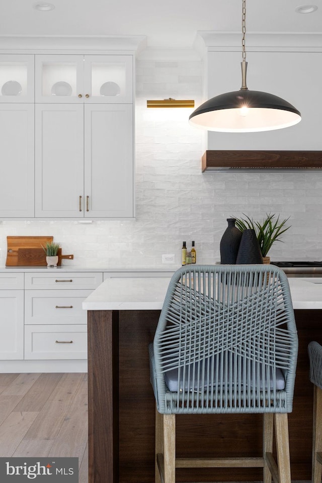 interior details featuring tasteful backsplash, wood finished floors, and crown molding