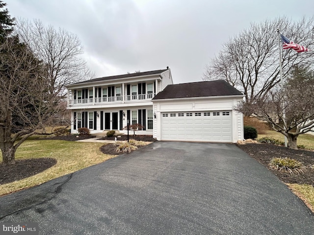 colonial inspired home with a balcony, an attached garage, french doors, and driveway