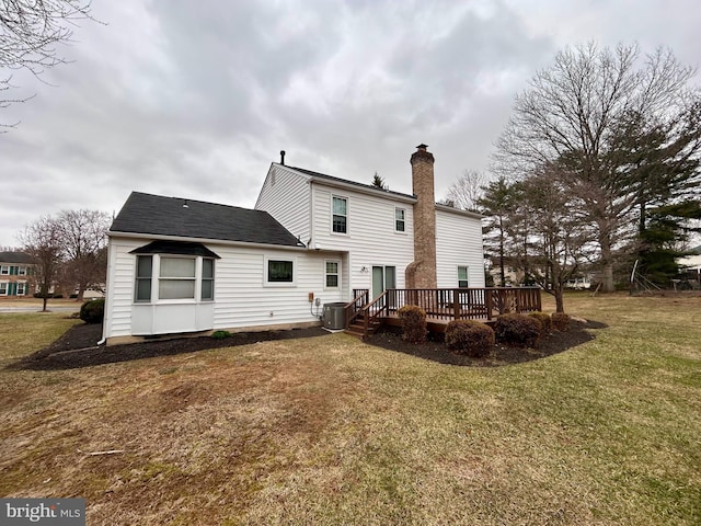 rear view of property featuring a chimney, central AC unit, a lawn, and a wooden deck