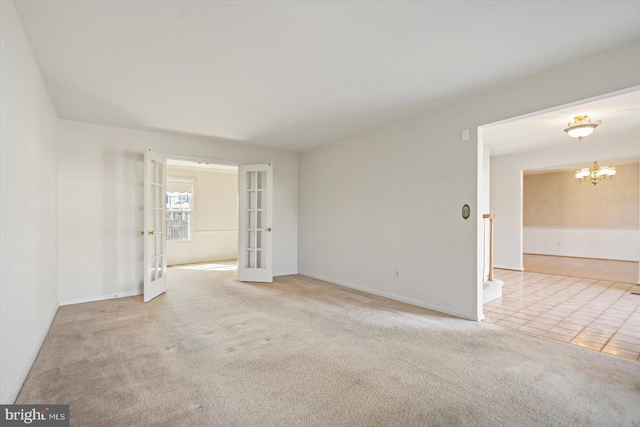 spare room featuring tile patterned flooring, baseboards, carpet, a chandelier, and french doors