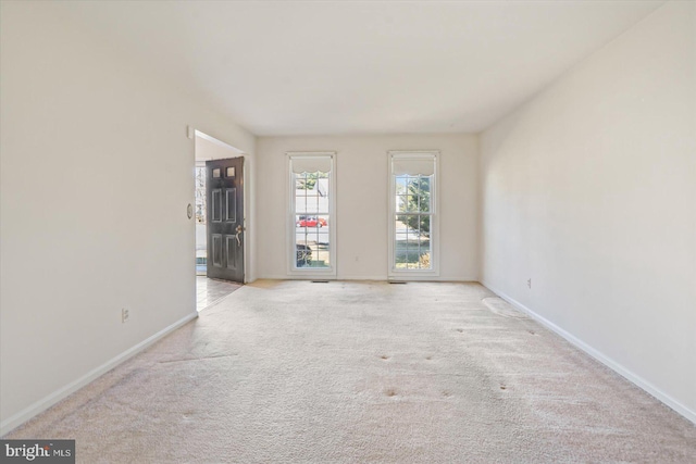 carpeted empty room featuring baseboards