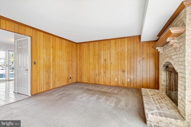 unfurnished living room featuring wooden walls, carpet, ornamental molding, and a fireplace