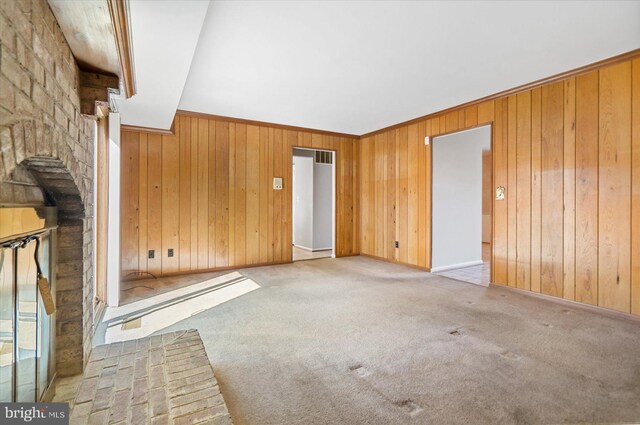 unfurnished living room featuring carpet flooring, baseboards, and wood walls