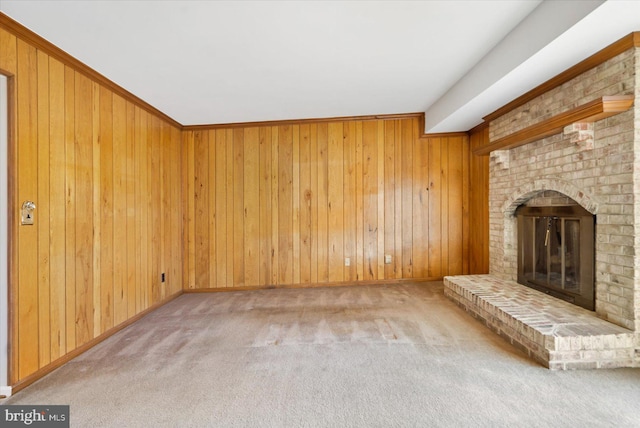 unfurnished living room featuring a brick fireplace, carpet flooring, and wood walls