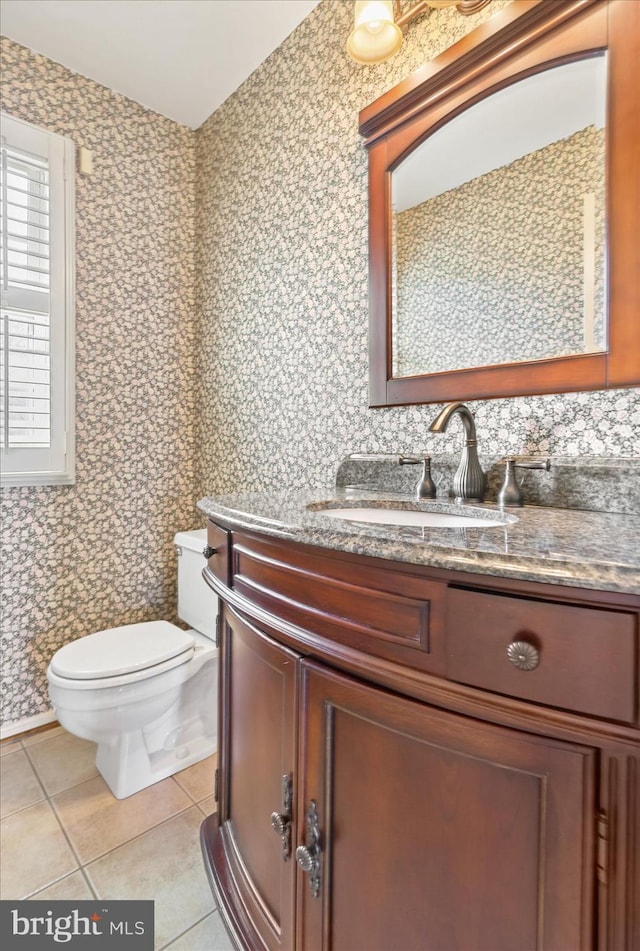 half bath with tile patterned floors, toilet, tile walls, and vanity