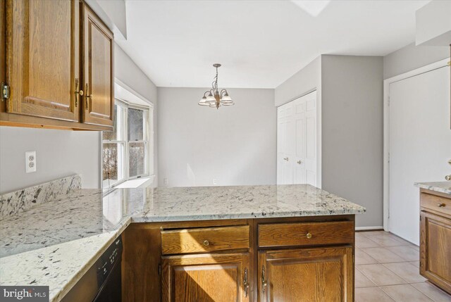 kitchen featuring light stone counters, brown cabinetry, light tile patterned floors, a peninsula, and decorative light fixtures