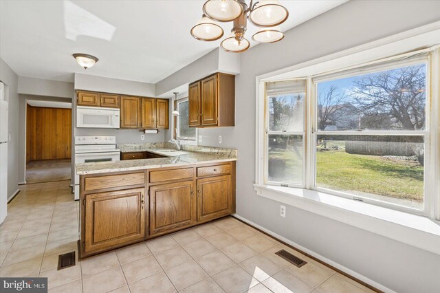 kitchen featuring visible vents, white appliances, brown cabinets, and light countertops