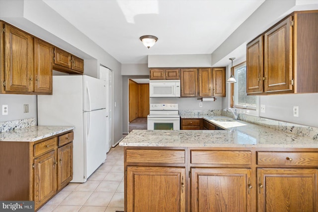 kitchen featuring a sink, white appliances, a peninsula, and brown cabinets