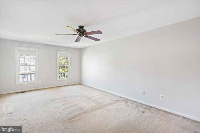 unfurnished room with visible vents, ceiling fan, baseboards, and carpet