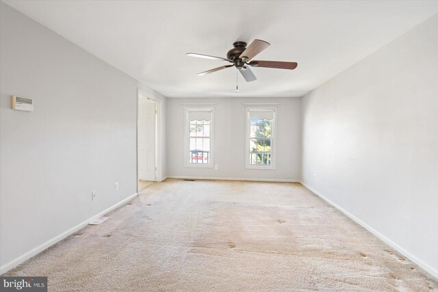 carpeted spare room featuring a ceiling fan and baseboards