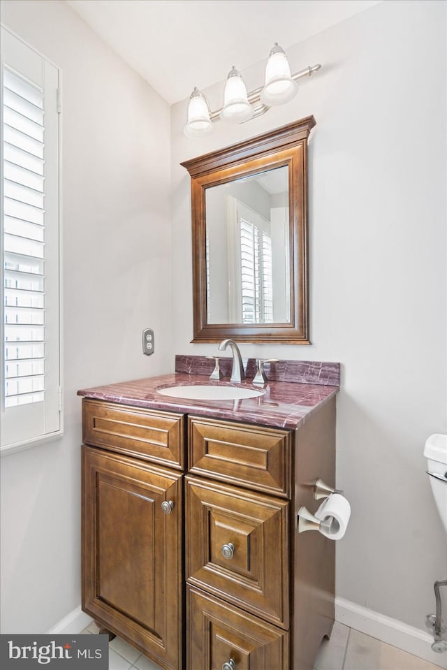 half bathroom featuring tile patterned floors, toilet, vanity, and baseboards