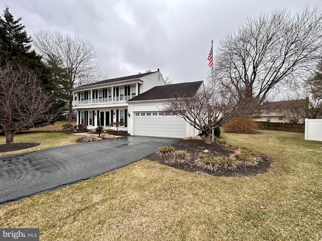 view of front facade featuring a front lawn, a balcony, a garage, and driveway