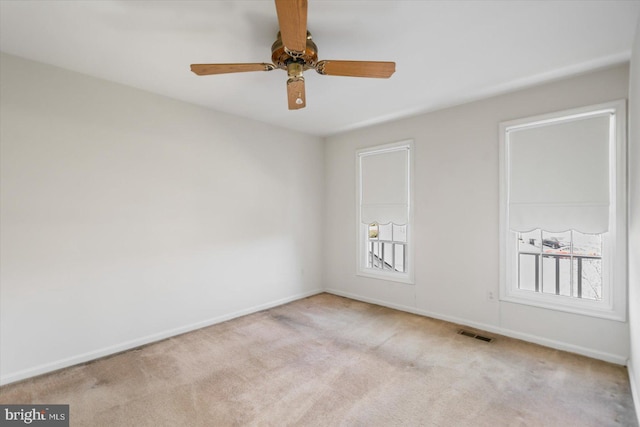 carpeted empty room featuring visible vents, a ceiling fan, and baseboards