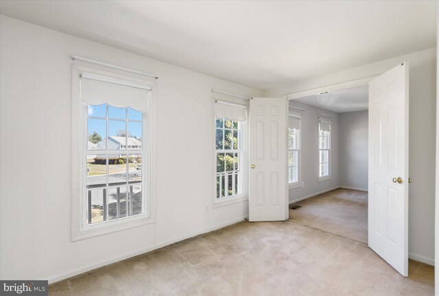 foyer with light colored carpet, visible vents, and baseboards