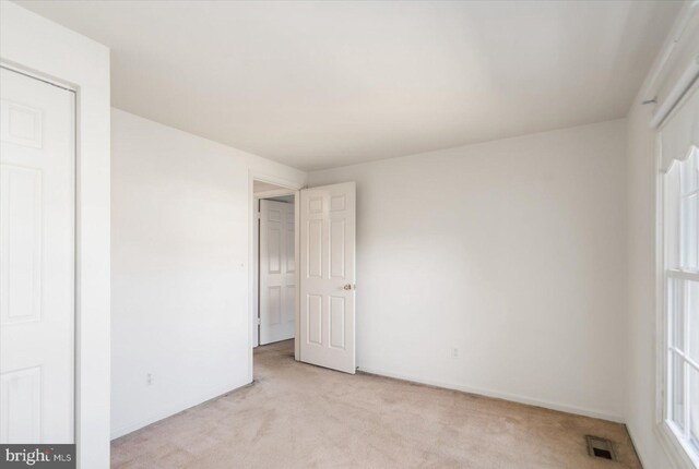 unfurnished bedroom with baseboards, visible vents, and light carpet