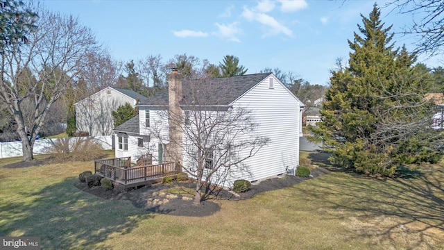 view of property exterior with a lawn, a chimney, a deck, and a shingled roof