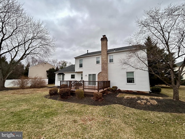 rear view of house with a wooden deck, a yard, and a chimney