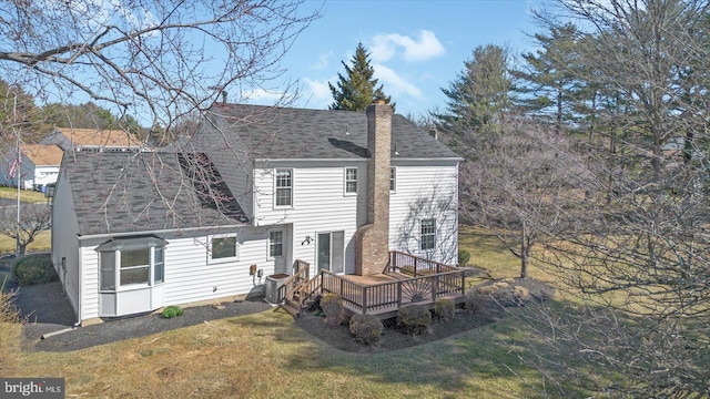 rear view of property featuring a yard, a wooden deck, a chimney, and a shingled roof