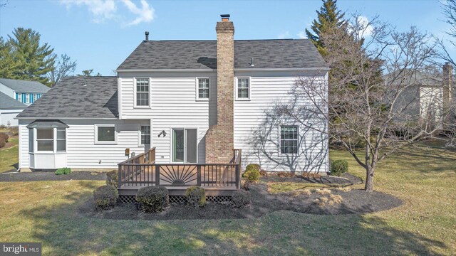 rear view of house featuring a lawn, roof with shingles, a deck, and a chimney