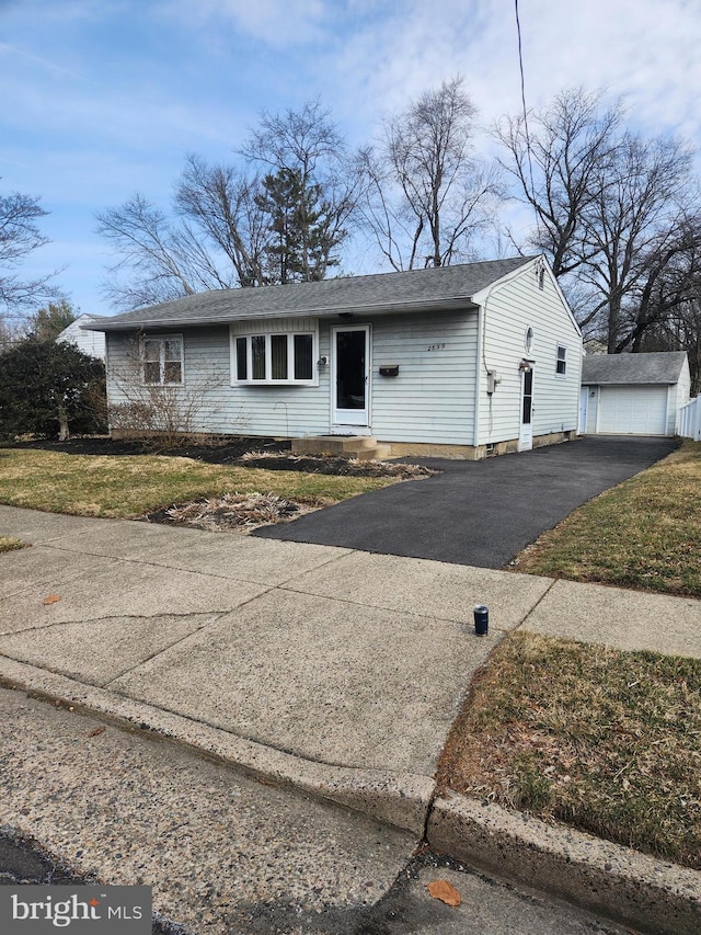 view of front facade featuring an outbuilding, driveway, and a front lawn