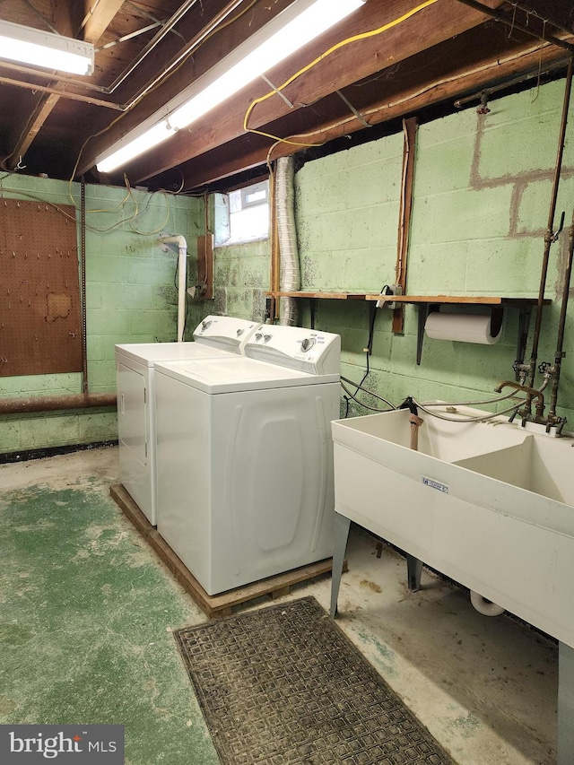 clothes washing area featuring laundry area, independent washer and dryer, and a sink