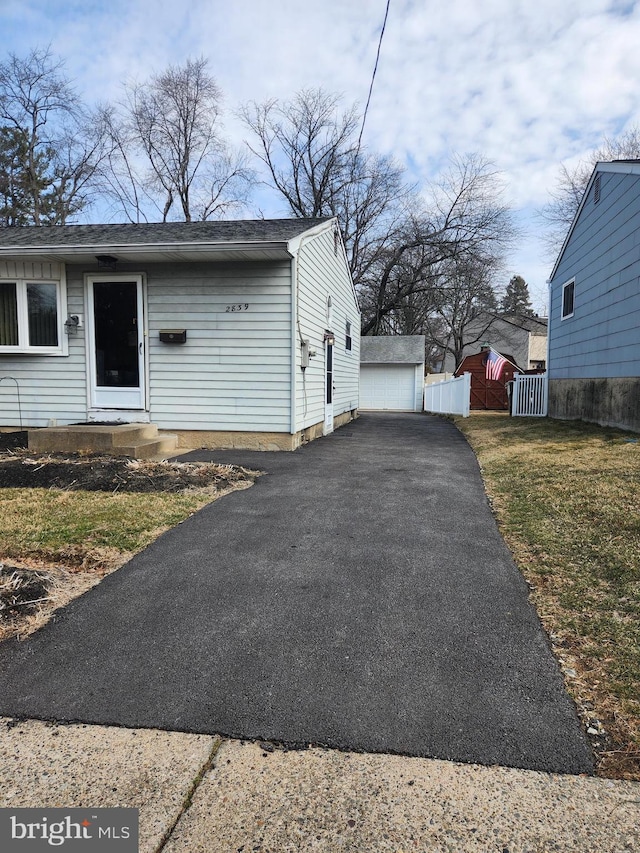 view of front of house with an outbuilding, a front lawn, and aphalt driveway