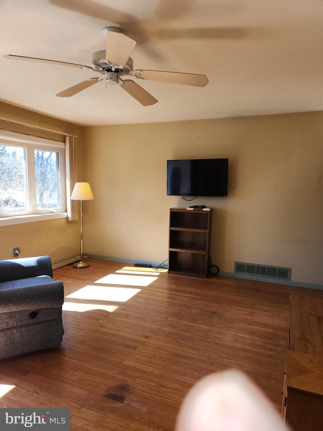 living area featuring ceiling fan, visible vents, and wood finished floors