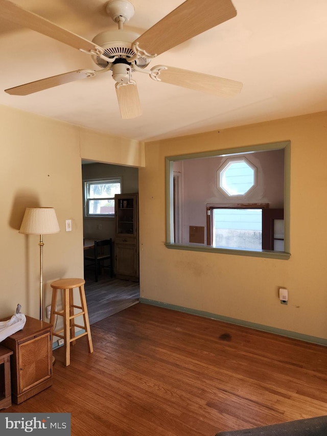 spare room featuring baseboards, wood finished floors, and a ceiling fan