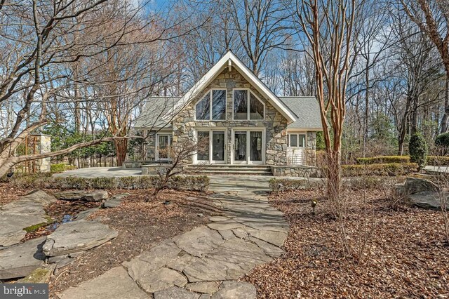 view of front of property featuring stone siding and a shingled roof