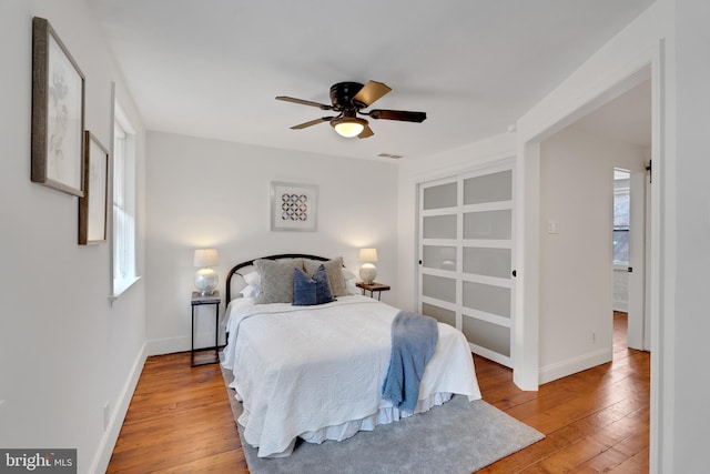 bedroom with baseboards, multiple windows, and hardwood / wood-style floors