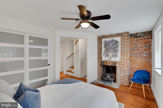 bedroom featuring baseboards, a ceiling fan, wood finished floors, and a fireplace