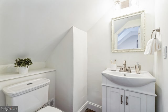 bathroom featuring baseboards, toilet, vanity, and vaulted ceiling