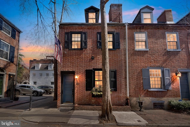 view of front of house featuring brick siding and a chimney