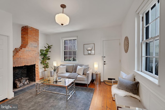 living area with wood-type flooring and a brick fireplace