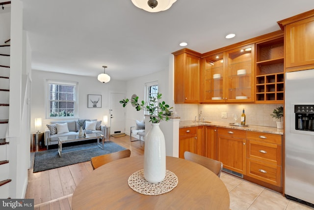 kitchen featuring brown cabinetry, stainless steel fridge with ice dispenser, and tasteful backsplash