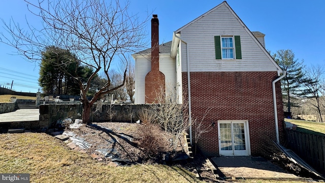 back of house featuring fence, brick siding, and a chimney