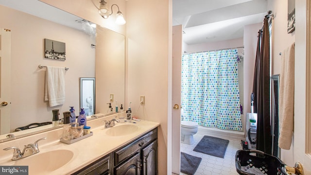 bathroom featuring double vanity, toilet, and a sink