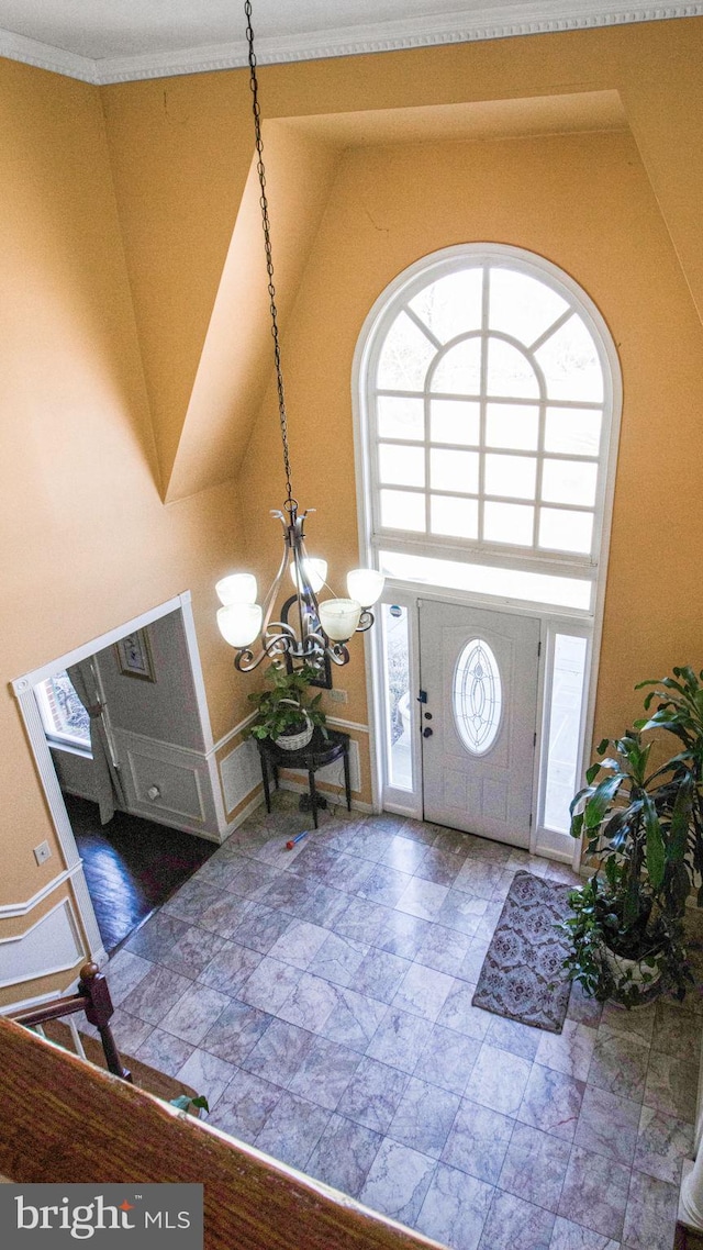 foyer with high vaulted ceiling, a healthy amount of sunlight, and a chandelier