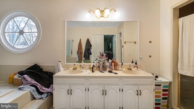 bathroom with double vanity, a relaxing tiled tub, a shower with curtain, and a sink