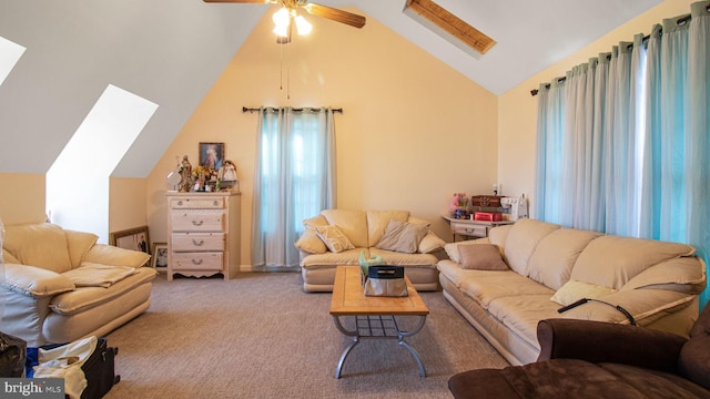 living room with a ceiling fan, vaulted ceiling with skylight, and carpet