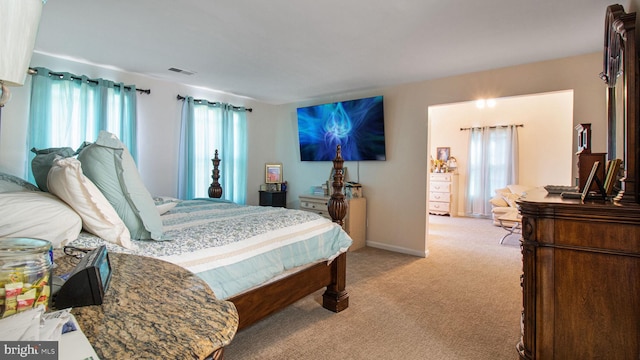 bedroom with light carpet, visible vents, multiple windows, and baseboards