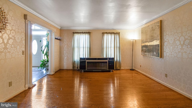 empty room featuring ornamental molding, wallpapered walls, decorative columns, and wood finished floors