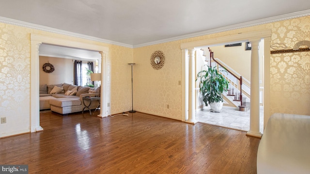 living room with stairway, wallpapered walls, ornate columns, and wood finished floors