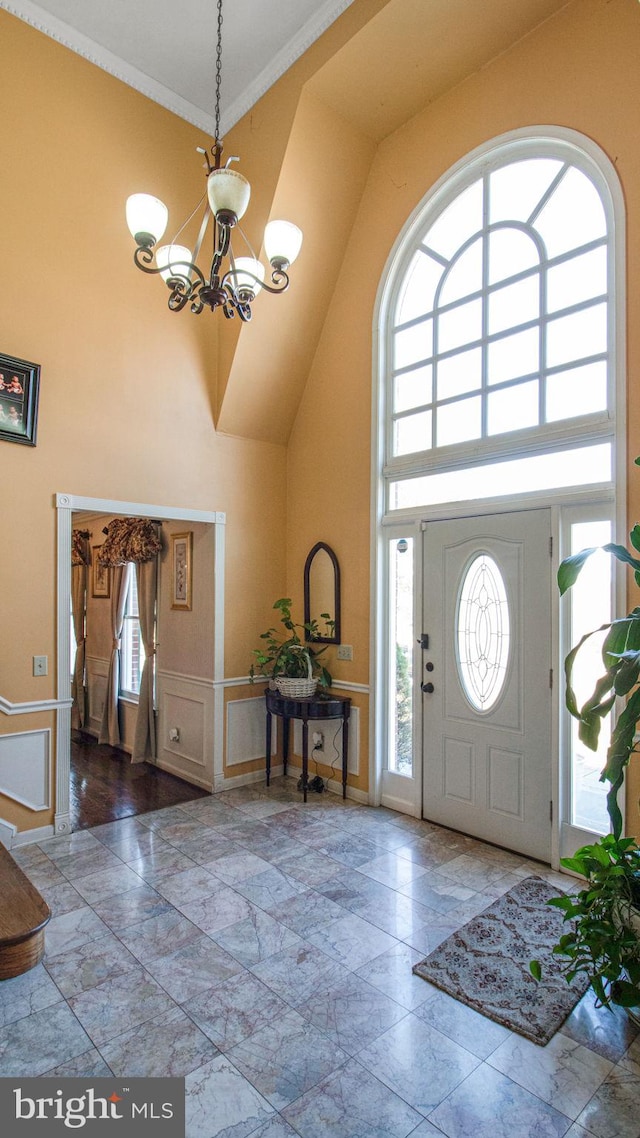 entrance foyer featuring a chandelier, a high ceiling, baseboards, and ornamental molding