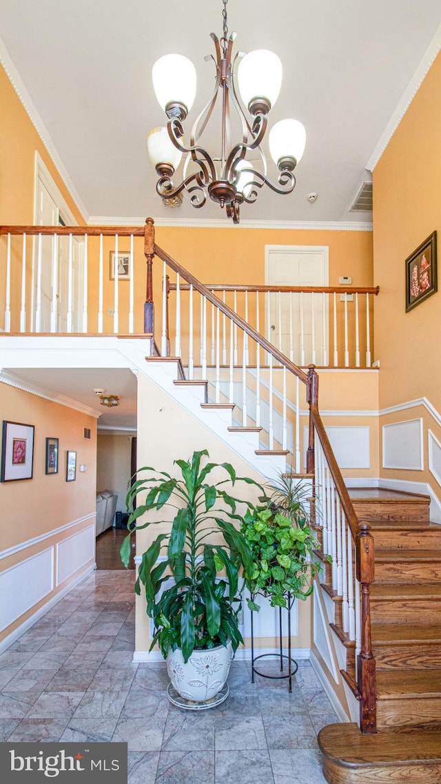 stairway with a chandelier, visible vents, and ornamental molding