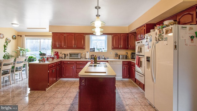 kitchen with a wealth of natural light, white appliances, a center island, and light countertops