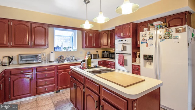 kitchen featuring a kitchen island, a toaster, pendant lighting, light countertops, and white appliances