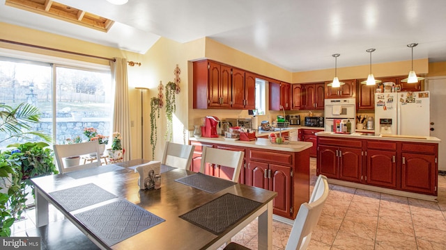 kitchen with white appliances, a peninsula, light countertops, decorative light fixtures, and a center island