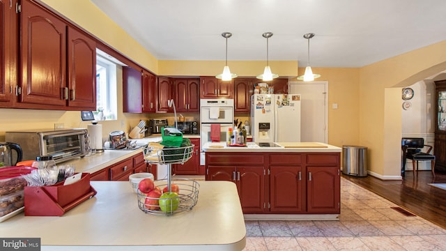 kitchen with white appliances, a center island, hanging light fixtures, and light countertops