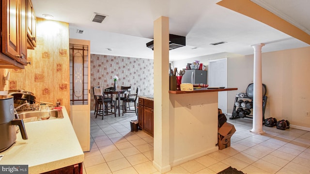 kitchen with visible vents, a sink, freestanding refrigerator, wallpapered walls, and ornate columns